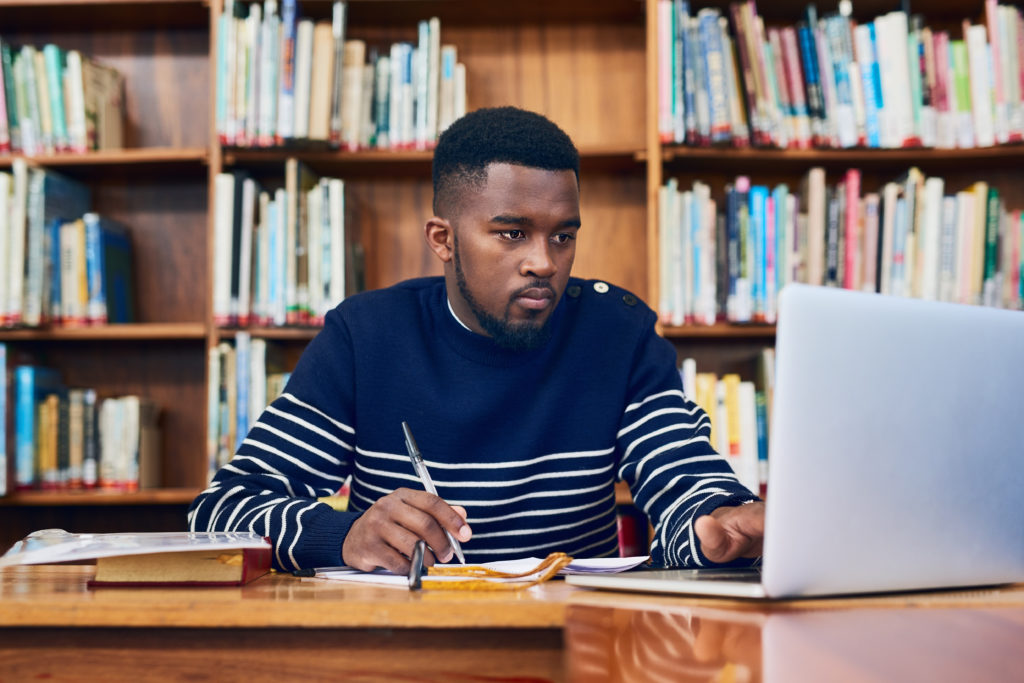 Young man working on laptop in library