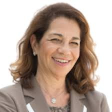 Portrait of a woman smiling against a plain background.